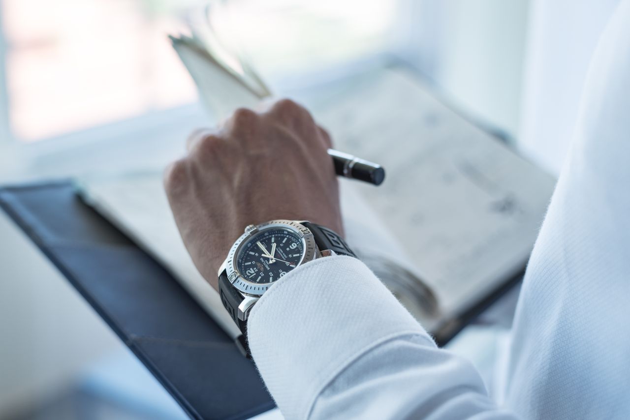 Close-up of a wristwatch on a persons wrist while writing in a diary.