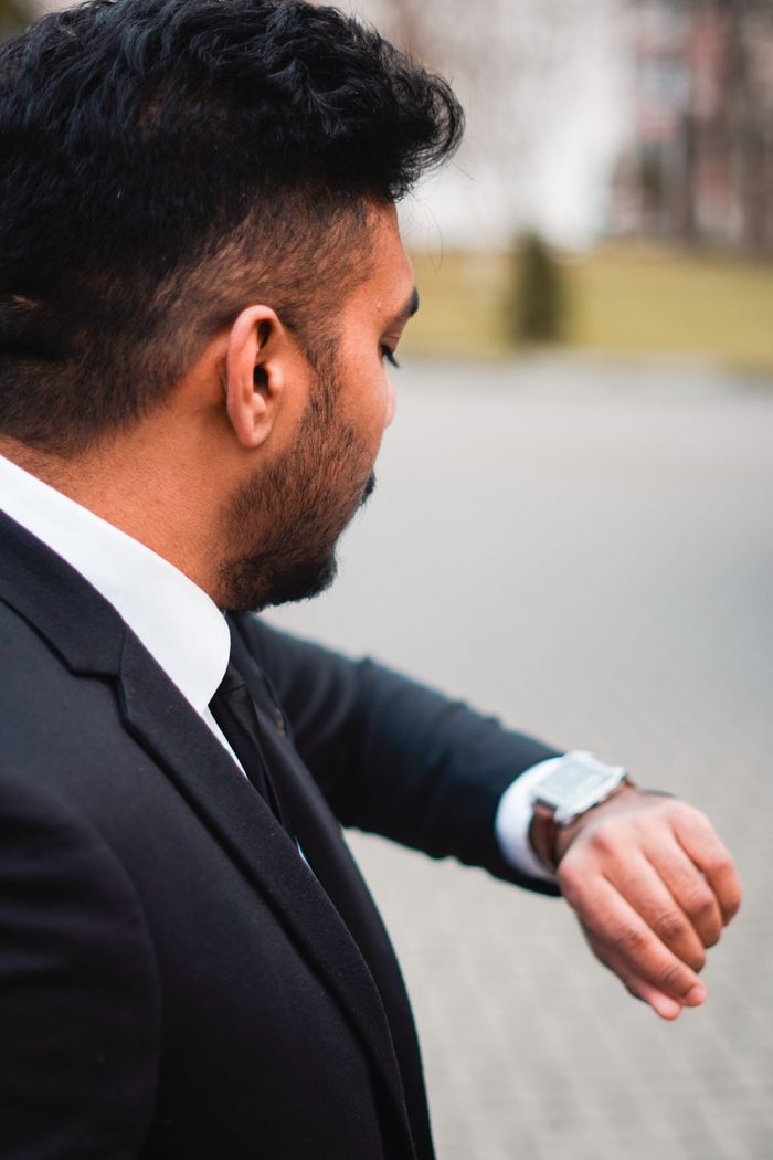 Man in a suit looking at his watch, symbolizing time management and professional punctuality.